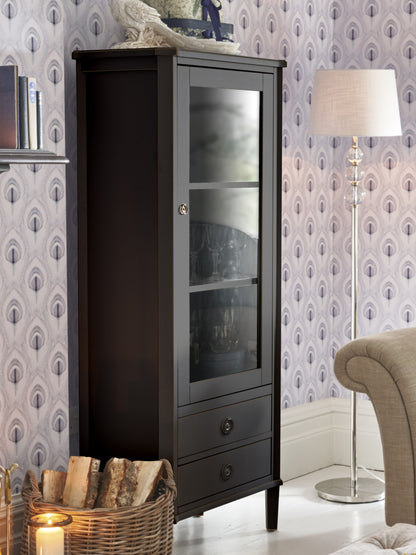 Dark wooden cabinet with glass doors in a room with patterned wallpaper and a lamp.