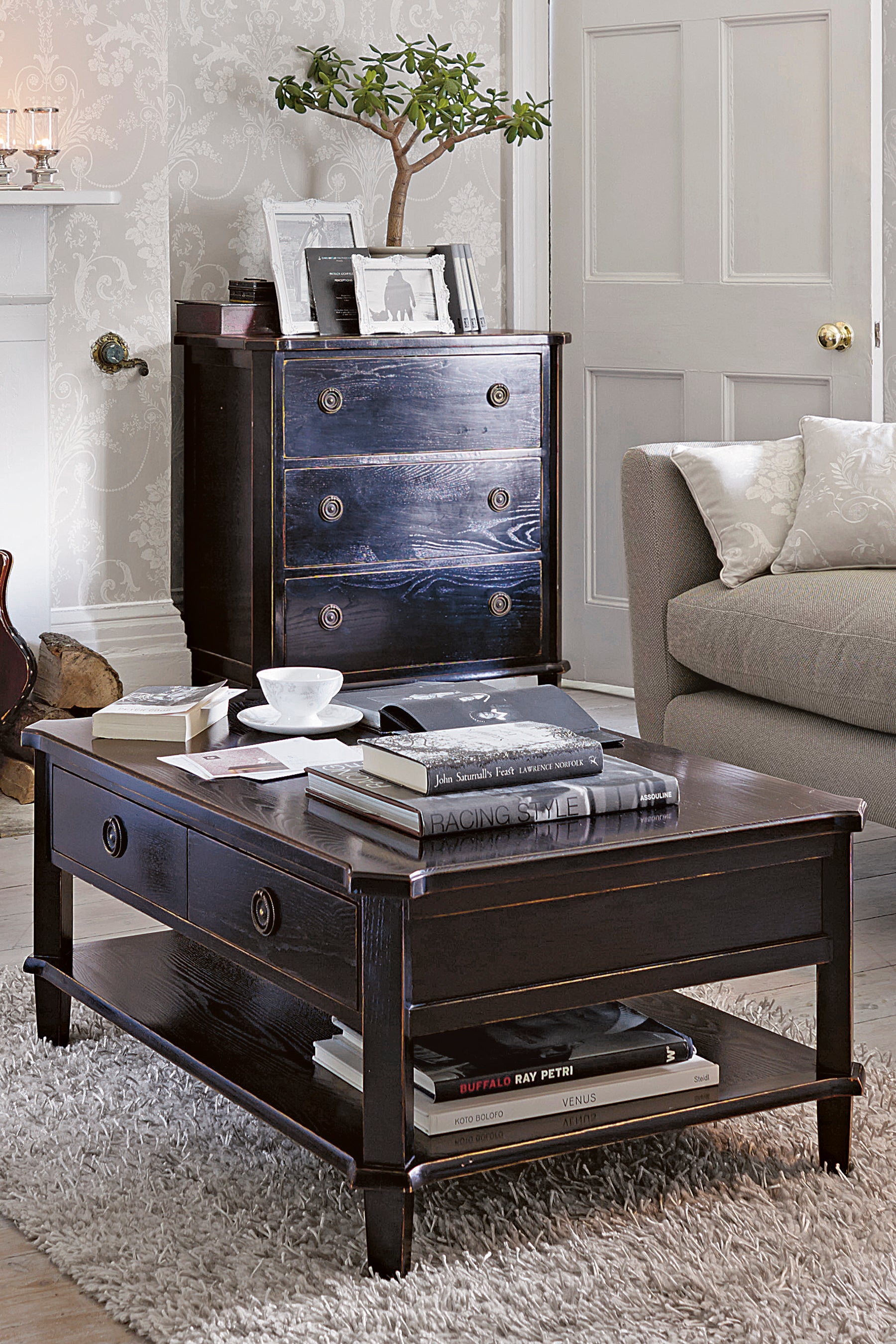 Dark wood coffee table with books and a cup in a living room setting.