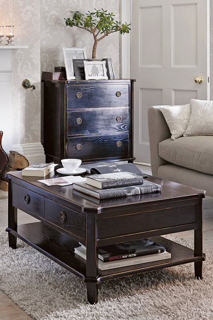 Dark wood coffee table with books and a cup in a living room setting.