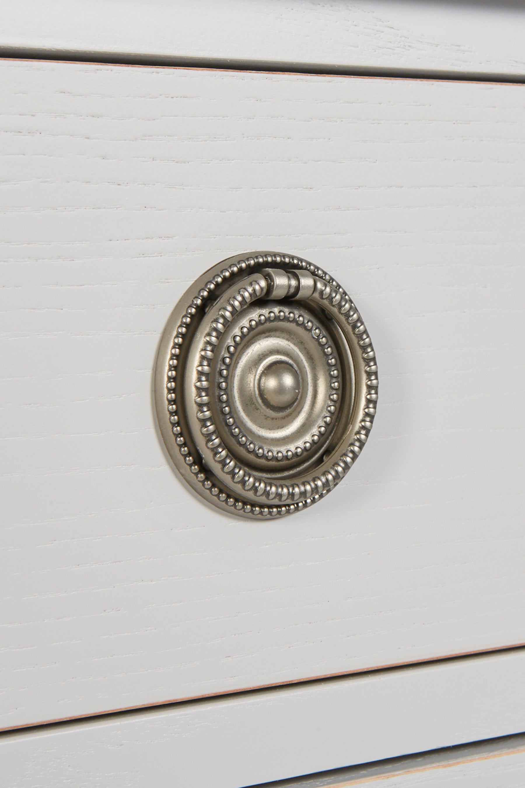 Close-up of a decorative cabinet knob on a white wooden surface