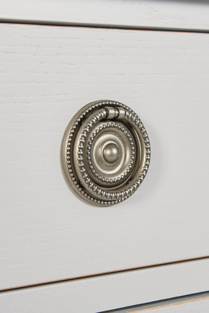 Close-up of a decorative cabinet knob on a white wooden surface