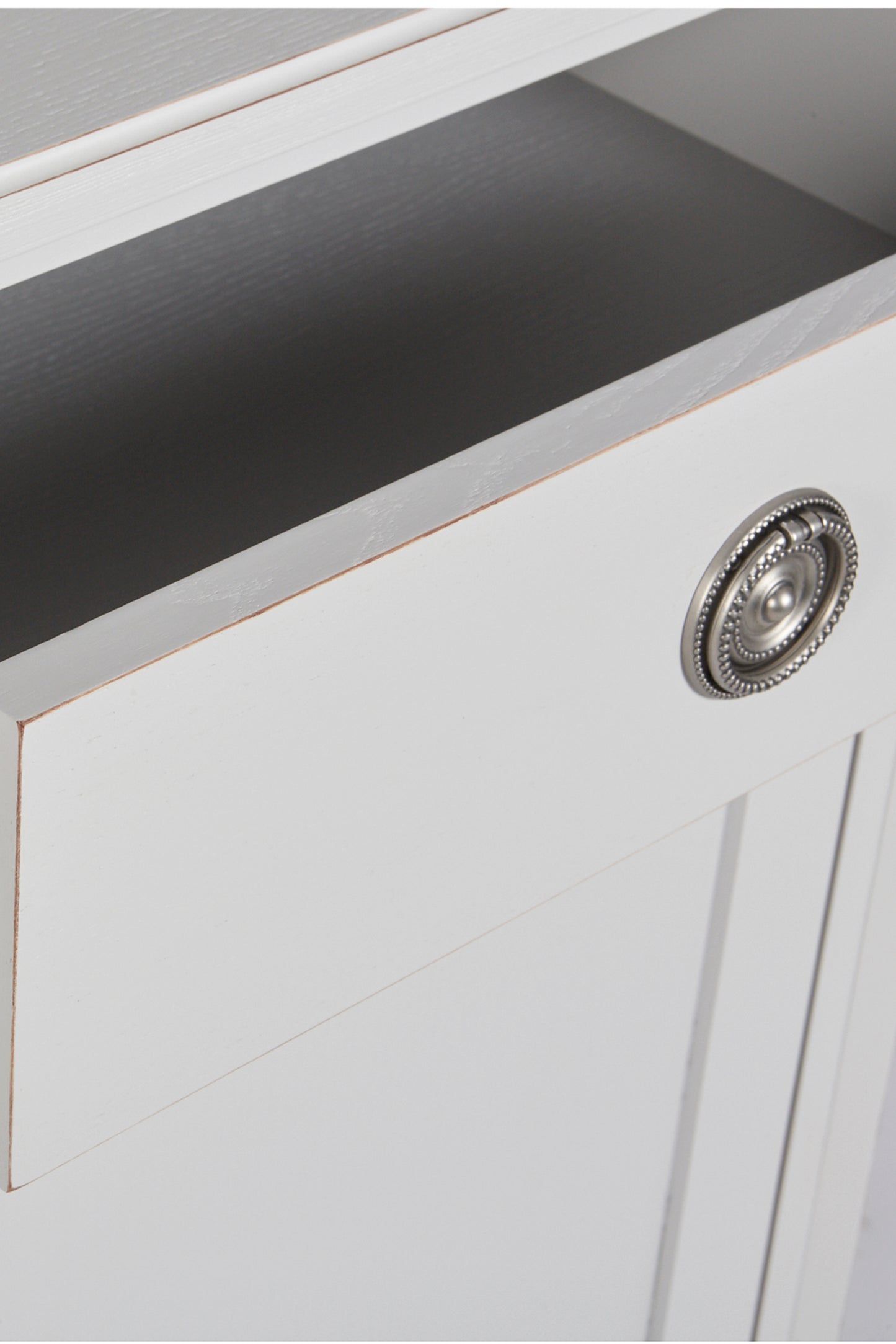 Close-up of a white cabinet with a decorative knob on a gray surface