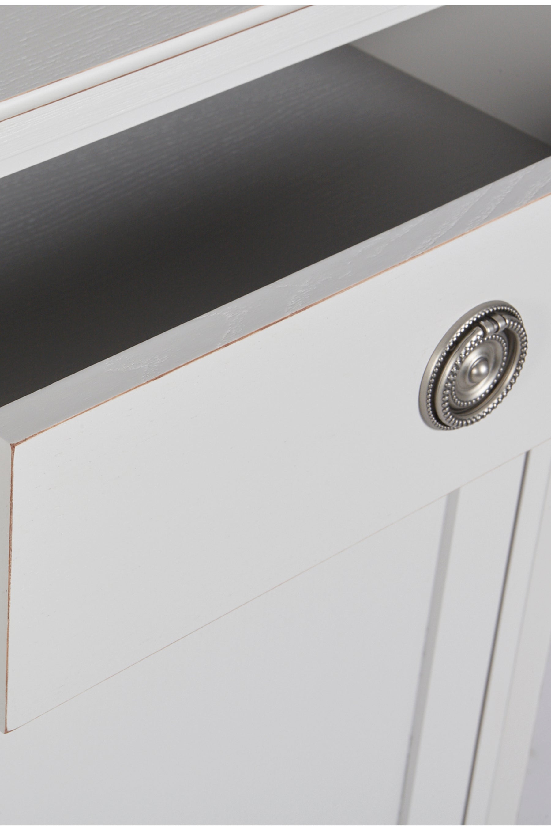 Close-up of a white cabinet with a decorative knob on a gray surface