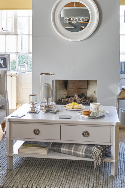 Living room with a coffee table, mirror, and fireplace.