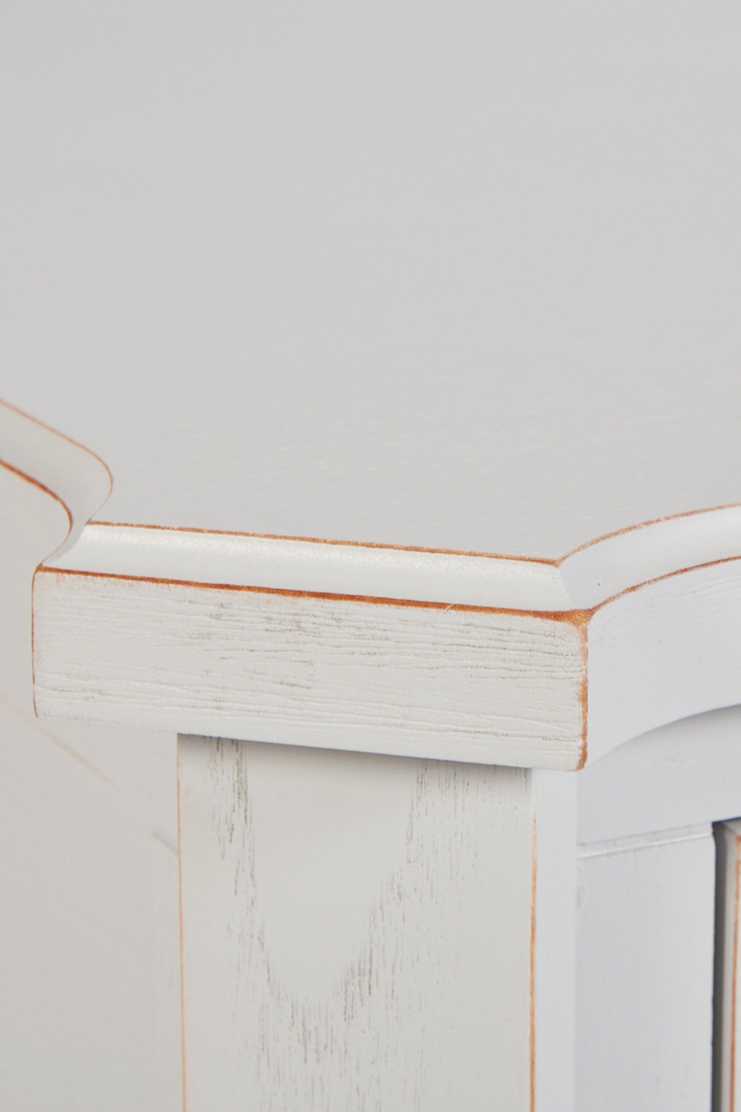 Close-up of a white wooden cabinet with a gold trim on a light gray background