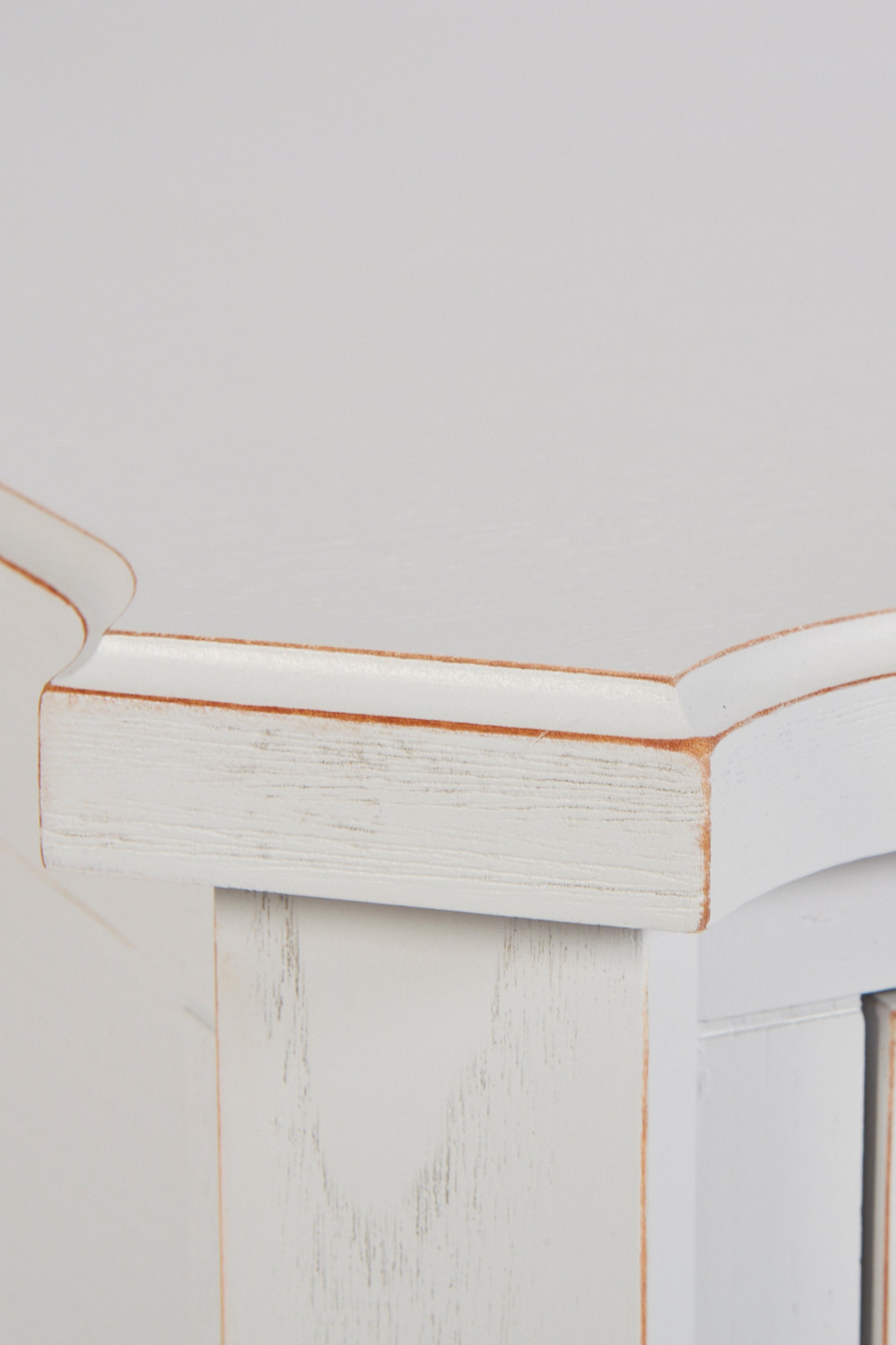 Close-up of a white wooden cabinet with a gold trim on a light gray background