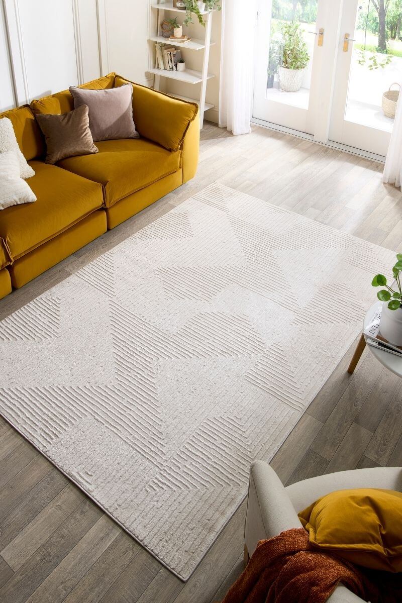 Living room with a yellow sofa, white rug, and a view of the outdoors.