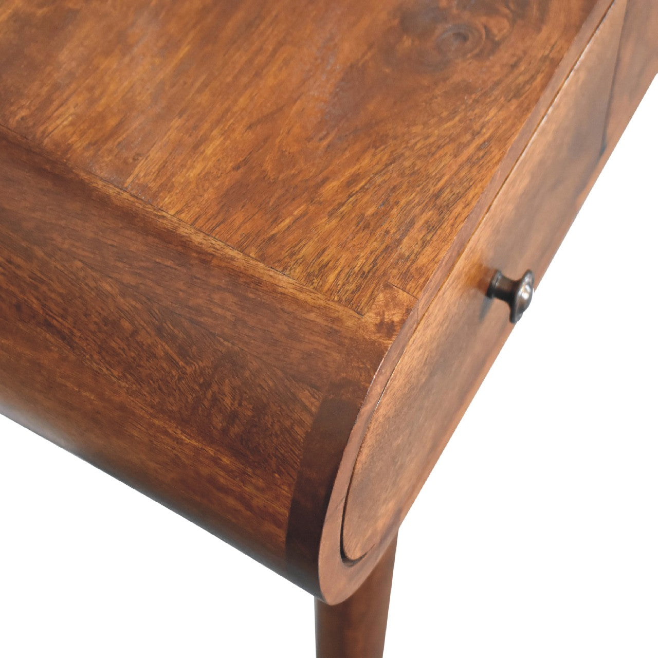 Bird's eye view of a close-up of the rounded corner edge of a wooden dressing table with a smooth finish and visible grain.