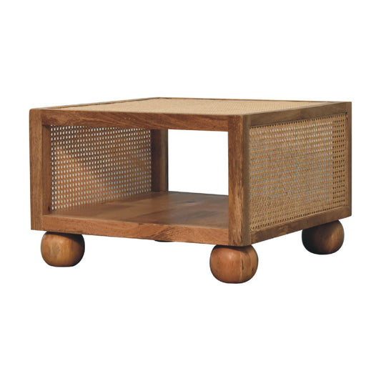 Square wooden coffee table with rattan panel sides, an open shelf, and four round ball feet.