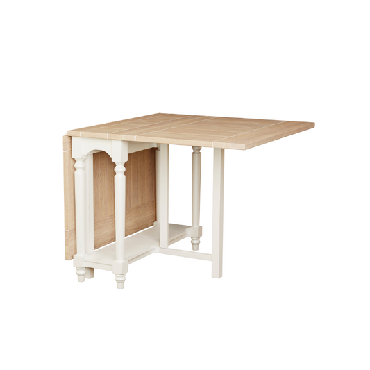A drop leaf dining table with a beige wooden surface and white frame, showing a compact design with one leaf folded under the main surface.
