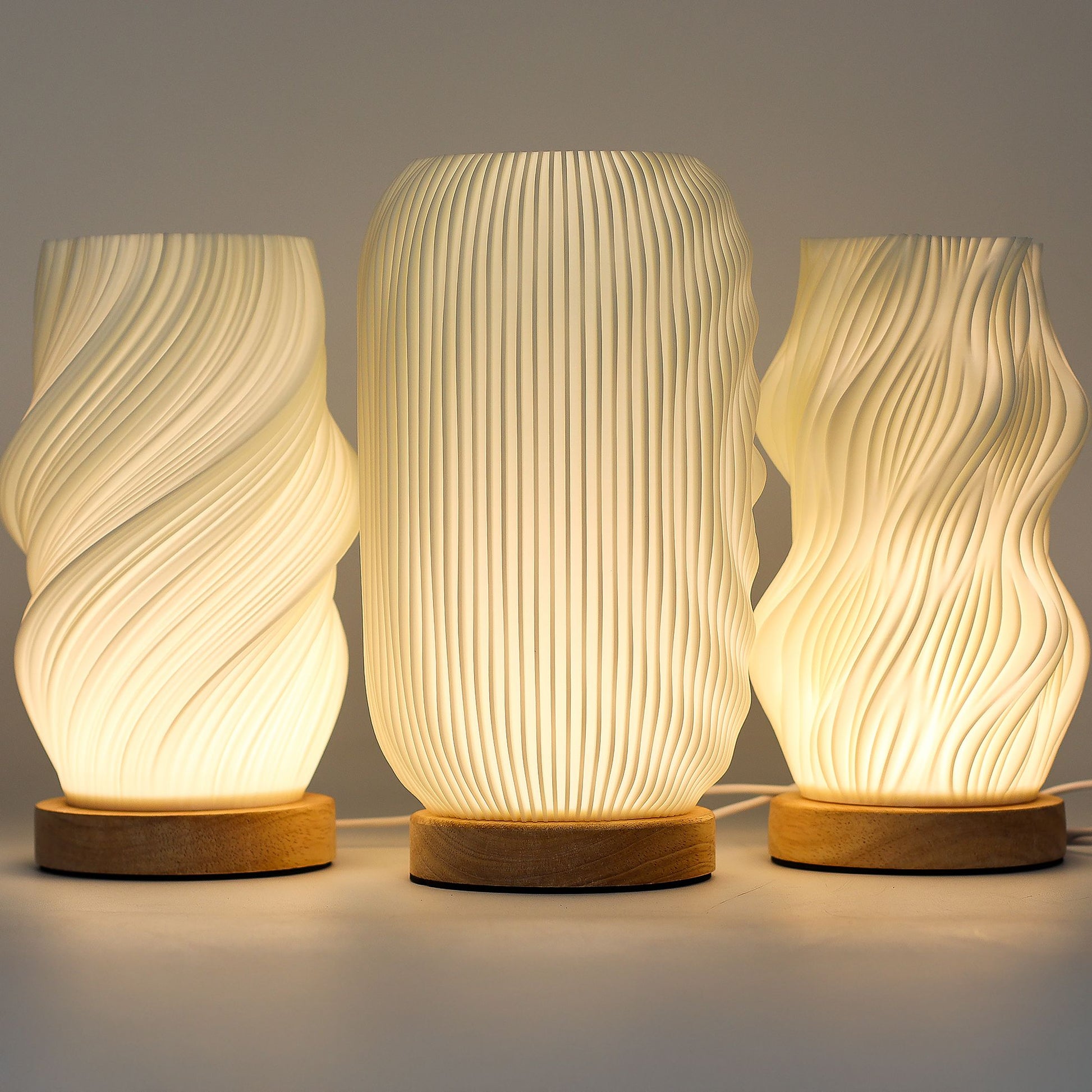 Three textured table lamps with wooden bases on a neutral background