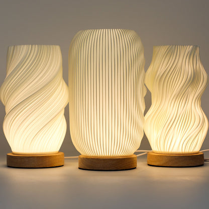 Three textured table lamps with wooden bases on a neutral background