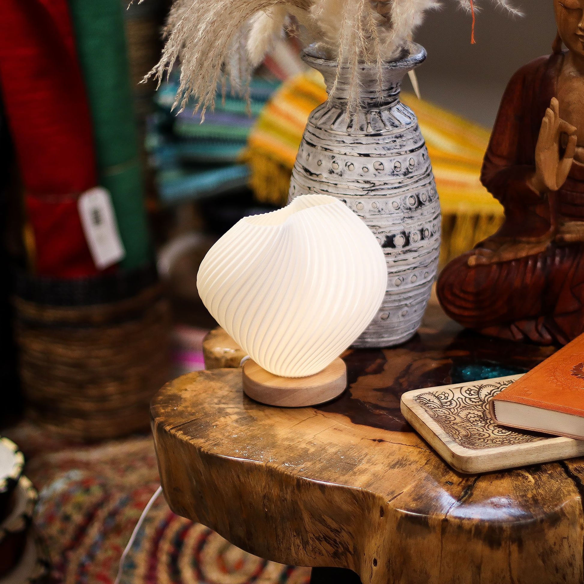 Decorative lamp on a wooden surface with a vase and statue in the background