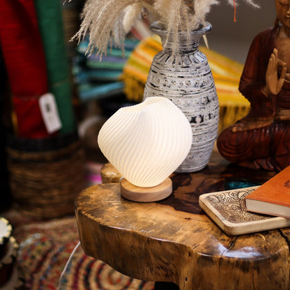 Decorative lamp on a wooden surface with a vase and statue in the background