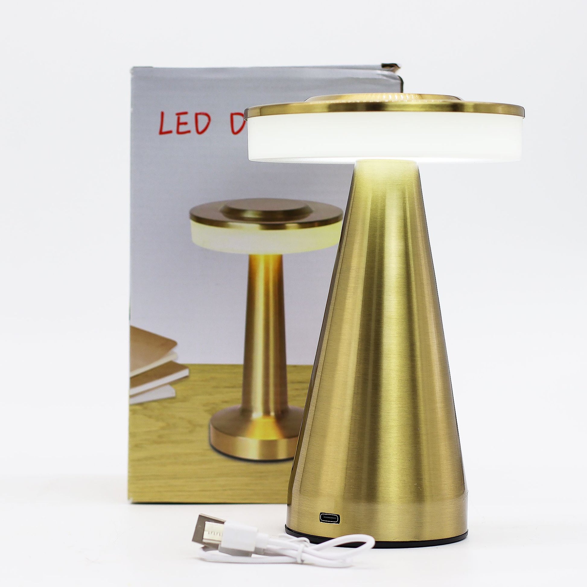 Gold table touch lamp with white shade and USB cable in front of packaging box on a white background