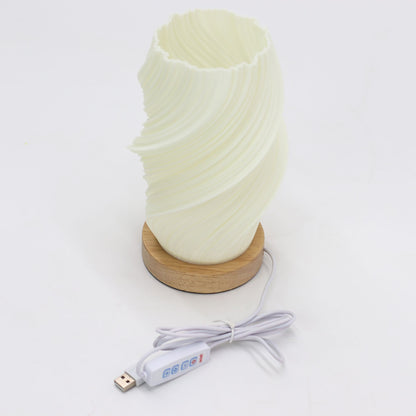 Cylindrical lamp with wavy design on a wooden base and USB cable on a white background