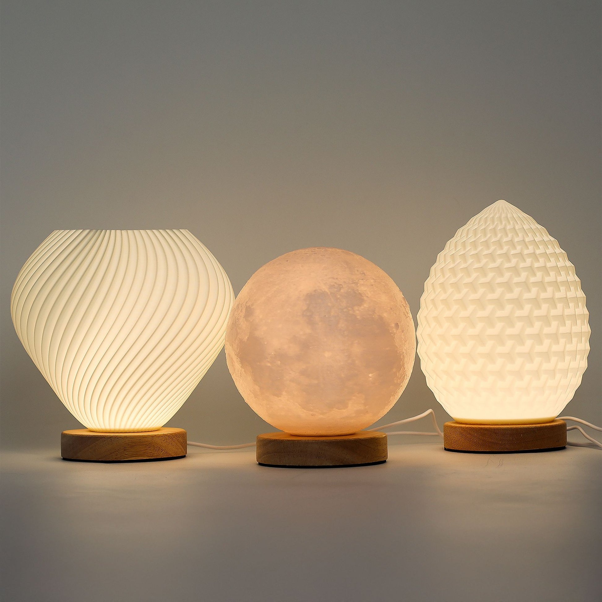 Three textured table lamps with wooden bases on a gray background