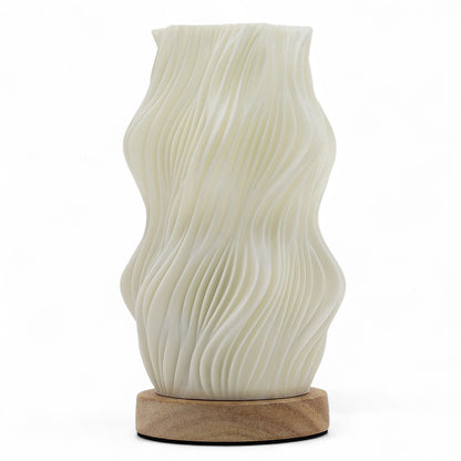 White ceramic table lamp with wavy design on a wooden base against a white background
