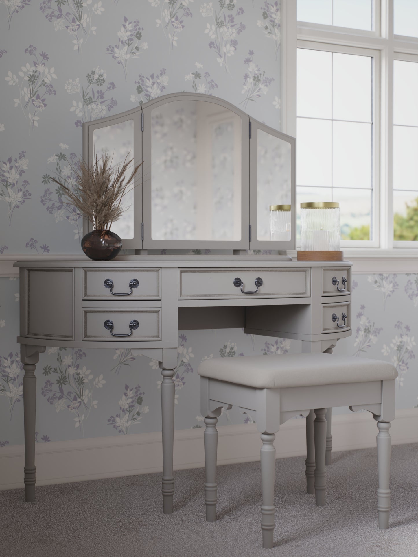 A Clifton Dove Grey 5 Drawer Dressing Table with a stool set in front of it. The table is large with multiple drawers and the stool is cushioned.