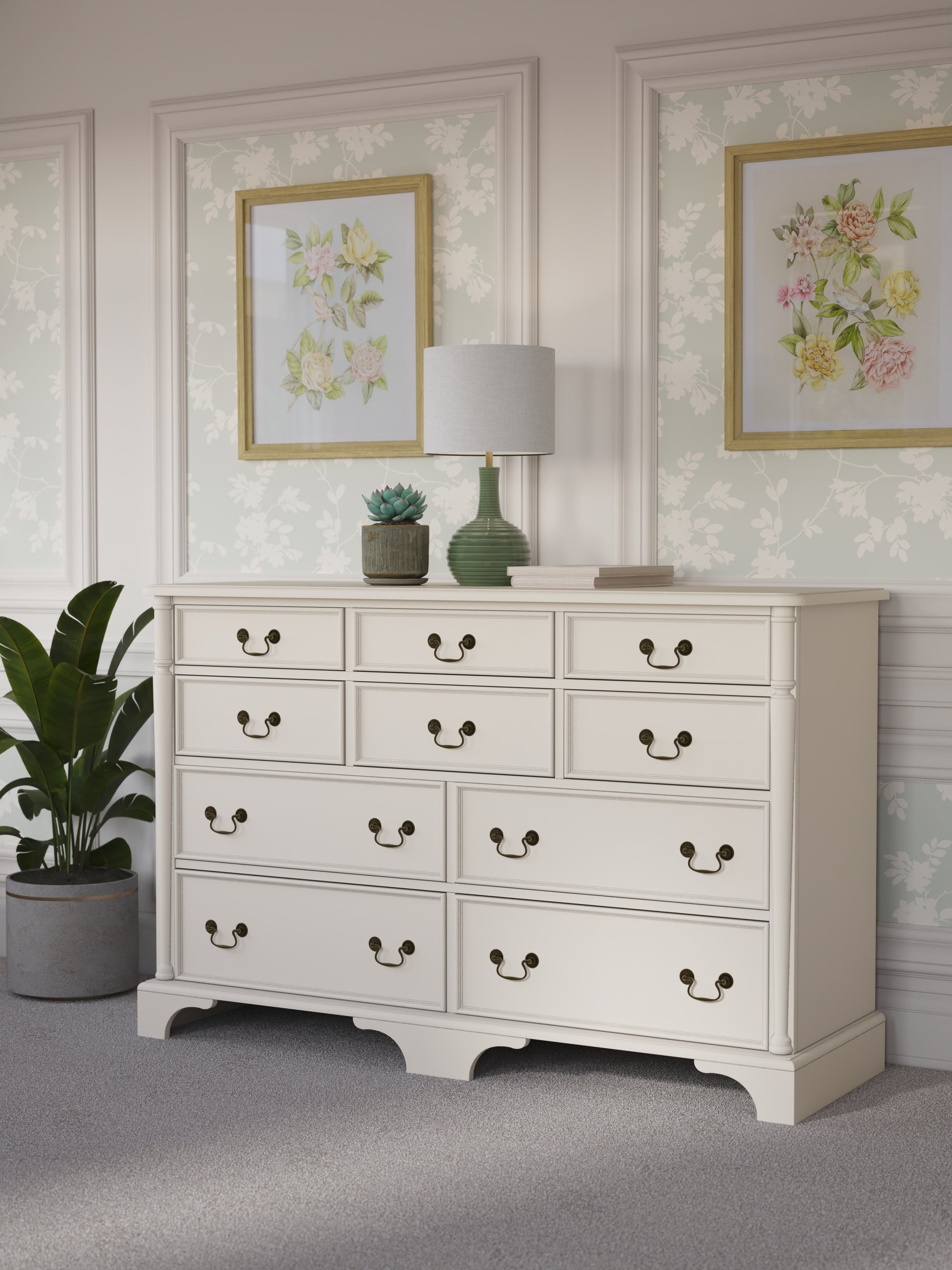 Ivory white dresser with multiple drawers in a room decorated with floral artwork and a plant.