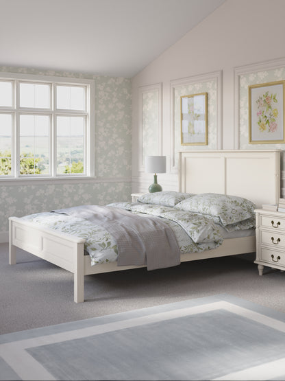 Bedroom with a white bed and floral bedding in a light setting.