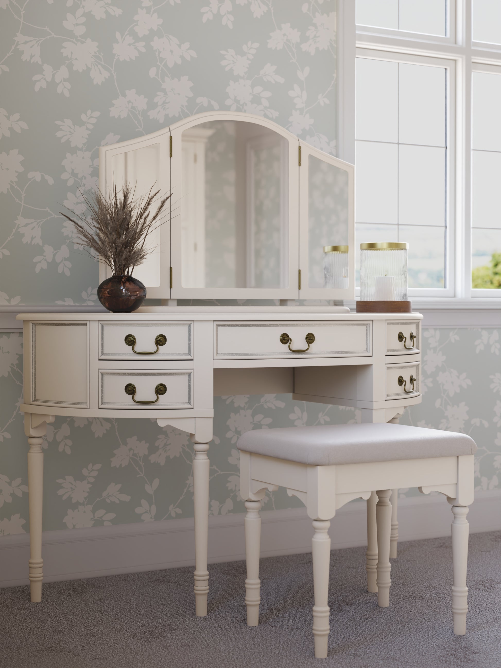 White vanity table with mirror and stool in a room with floral wallpaper.