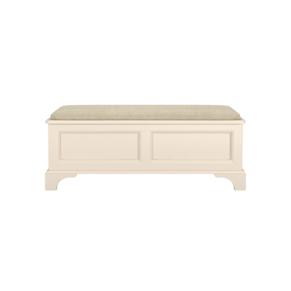 An ivory-coloured wooden blanket box with a cushioned lid, featuring a traditional design with panelled sides and a straight base.