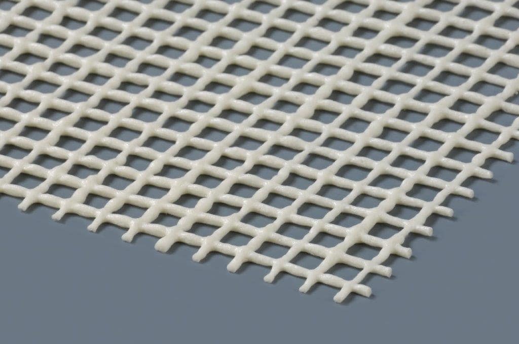 Close-up of a white woven mesh rug gripper on a grey background