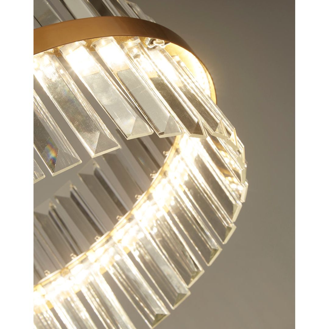 Close-up of a modern chandelier with clear glass and gold accents on a neutral background