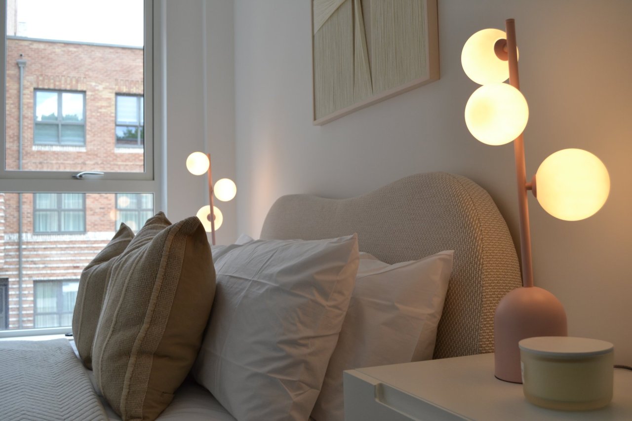 Cozy bedroom with pillows on a bed and decorative lamps.